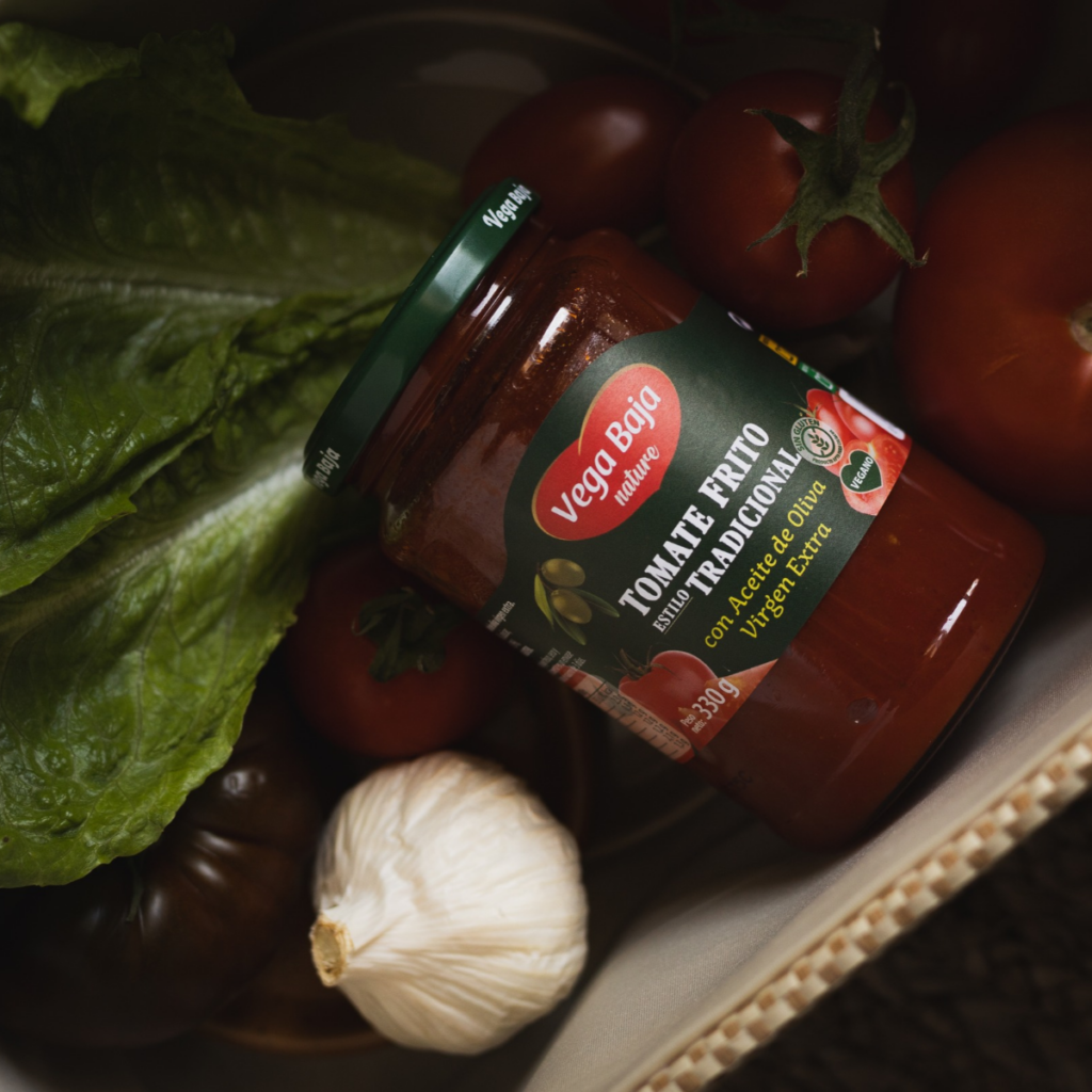 7 ideas de recetas fáciles para la vuelta a la rutina 1 | Vega Baja Conservas Tarro de tomate frito tradicional Vega Baja acompañado de tomates frescos, lechuga y ajo, representando ingredientes naturales y sabor casero.